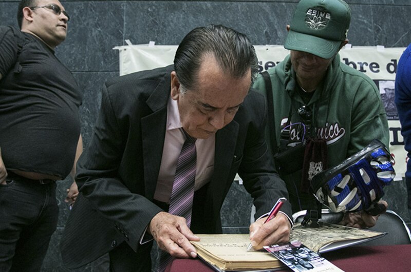 El expresidente mexicano Luis Echeverría Álvarez firma un libro.