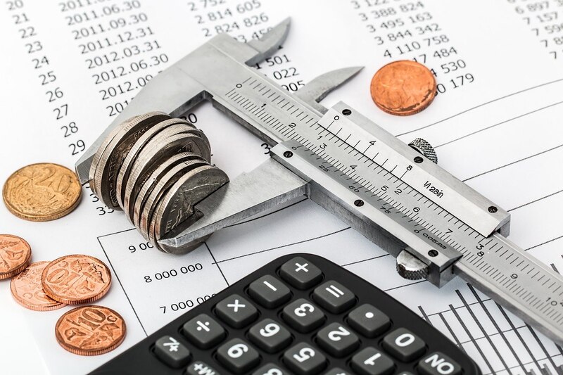 Calculadora, monedas y cinta métrica sobre una factura