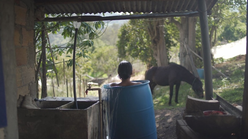 Mujer tomando un baño en una tina azul en el campo