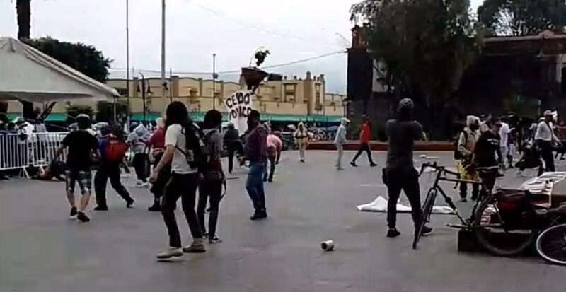 Posible título: Enfrentamiento entre manifestantes y policías en el zócalo de la Ciudad de México