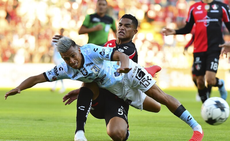 Dos jugadores de fútbol se disputan el balón.