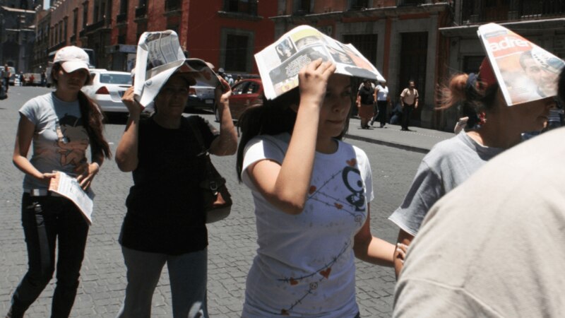 Mujeres se protegen del sol con periódicos