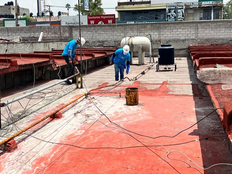 Dos trabajadores impermeabilizando un techo