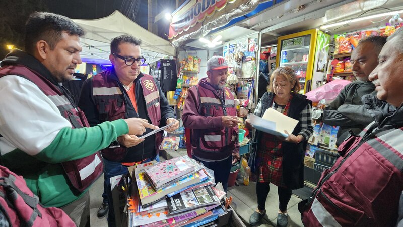Un grupo de personas están mirando unos libros en un puesto de la calle.