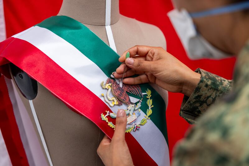 Mujer militar hace pruebas para comenzar a bordar con hilo dorado el Escudo Nacional