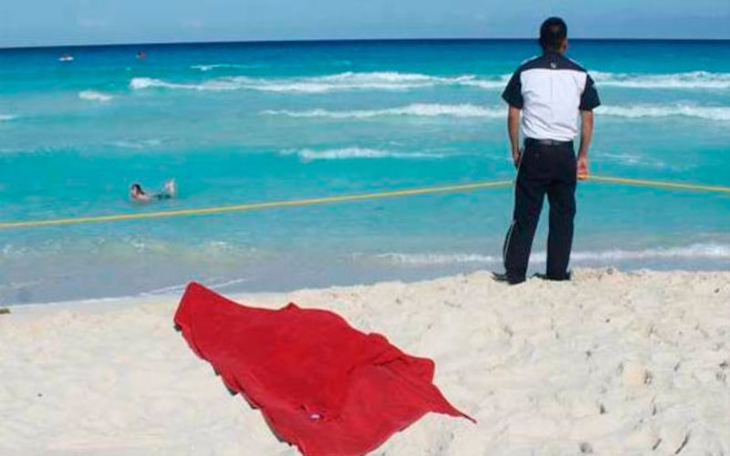 Un hombre observa cómo una niña se baña en el mar