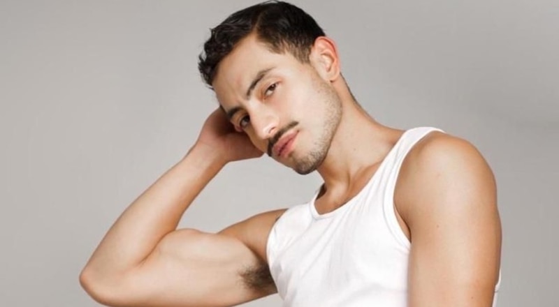 Joven hispano con bigote y cabello negro peinado hacia atrás