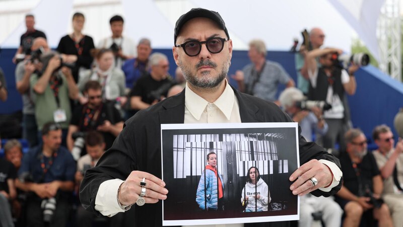 El director de cine Pedro Almodóvar sostiene una fotografía de los actores Penélope Cruz y Javier Bardem en la alfombra roja del Festival de Cine de Cannes.