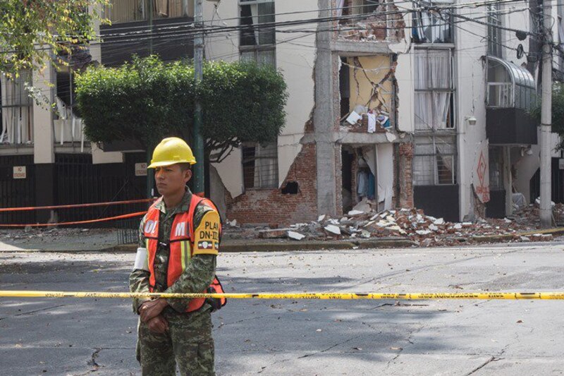 Un soldado custodia un edificio dañado por un terremoto.