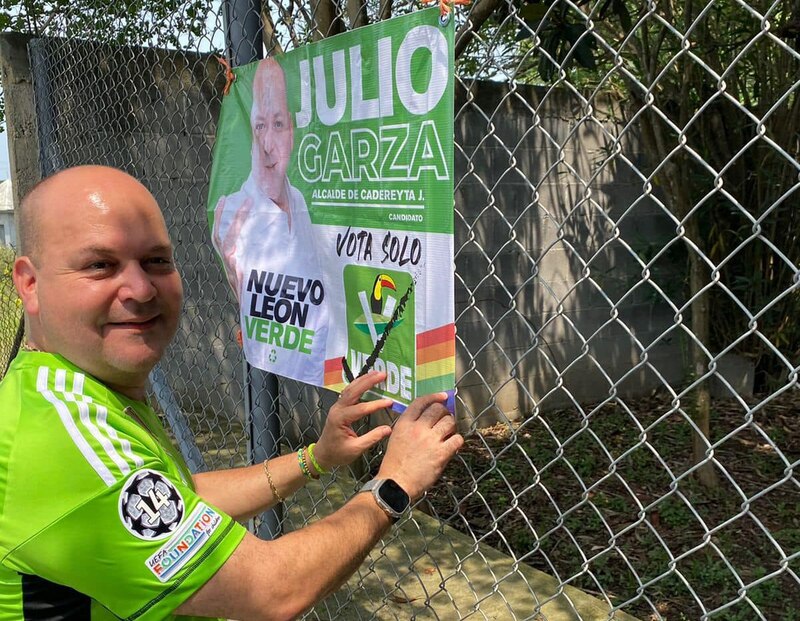Candidato Julio Garza coloca cartel en una valla