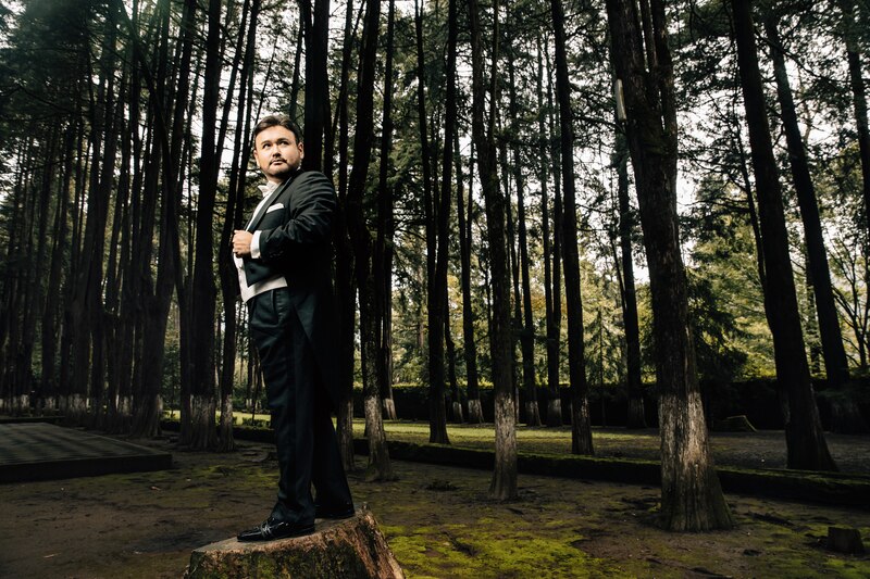Elegante hombre con traje negro en el bosque
