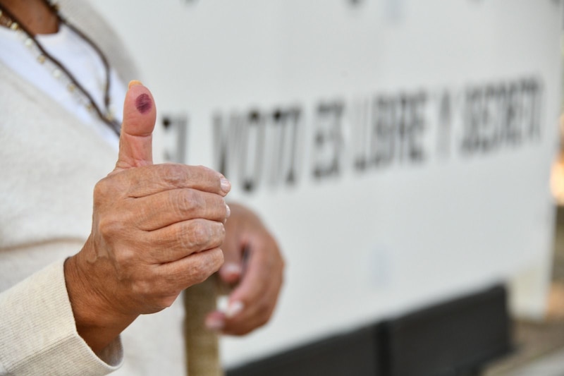 Mujer muestra su pulgar con tinta electoral