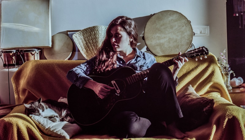 Mujer tocando la guitarra en el sofá