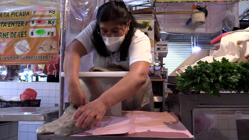 Mujer preparando carne en un mercado