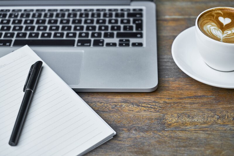 Una taza de café y un portátil sobre una mesa de madera