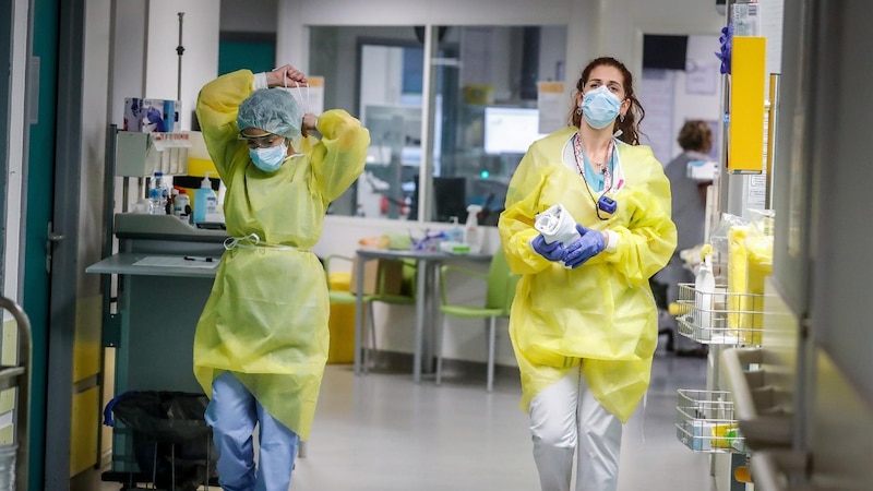 Dos enfermeras con trajes de protección contra el coronavirus caminan por un pasillo de un hospital.