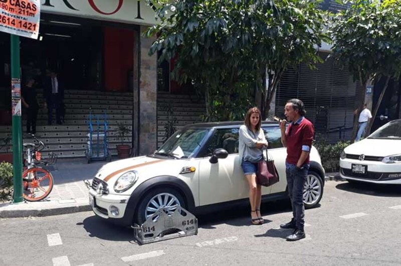Un Mini Cooper blanco estacionado en la calle con una llanta bloqueada
