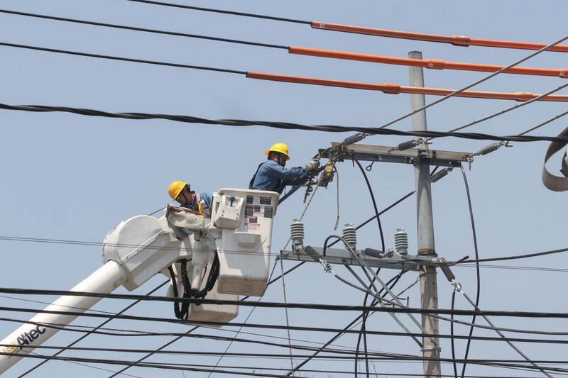 Dos trabajadores de la compañía eléctrica arreglando un cable en la ciudad de México