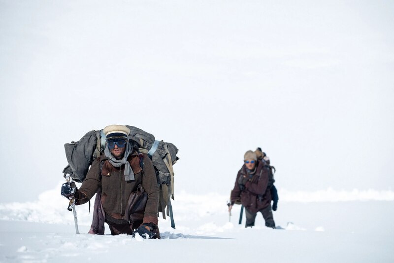 Dos hombres caminan por la nieve.