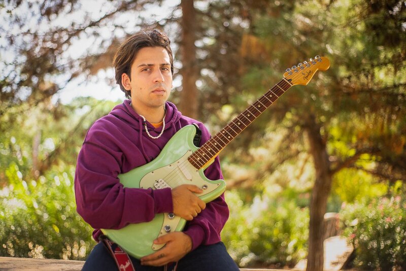 Joven tocando la guitarra en un parque