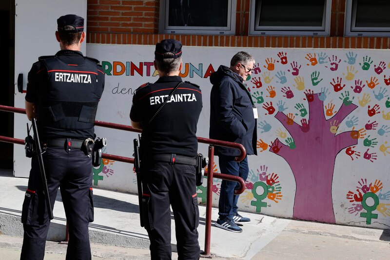 Dos policías de la Ertzaintza vigilan la entrada a un colegio electoral
