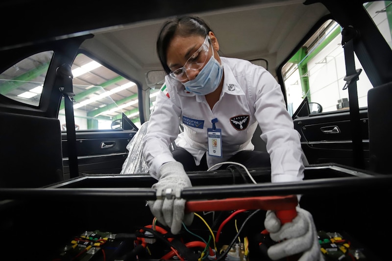 Mujer trabajando en un auto eléctrico