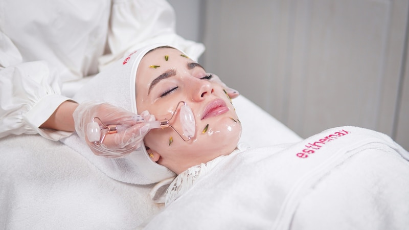 Una mujer recibiendo un masaje facial en el rostro