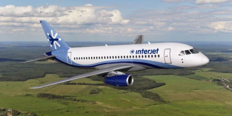 Un avión de Interjet vuela sobre un campo verde