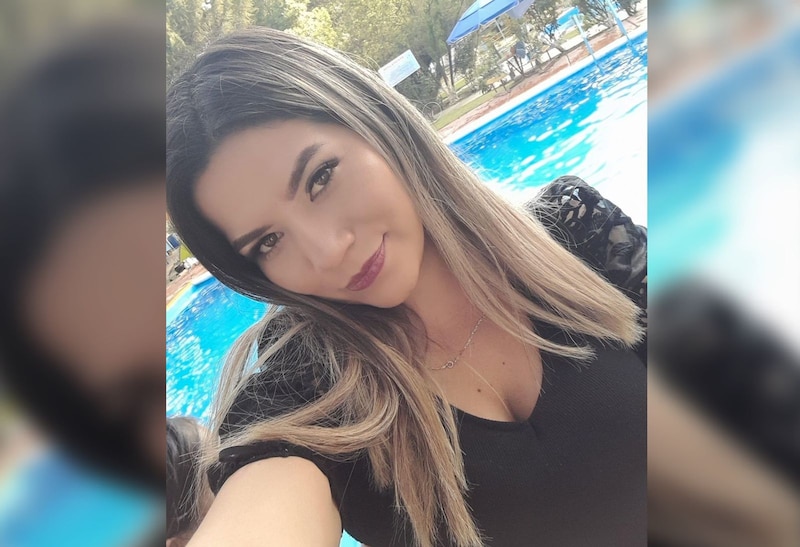 Mujer joven en traje de baño negro se toma una selfie junto a una piscina