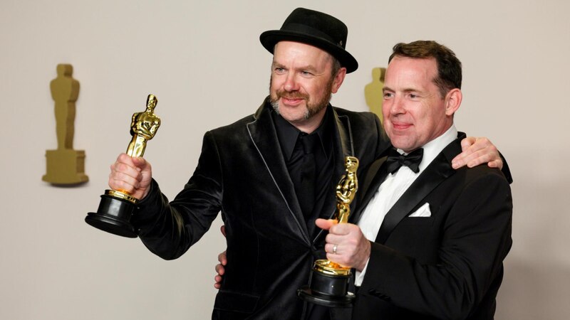 Los ganadores del Oscar a Mejor Guion Original, Martin McDonagh (izquierda) y John Michael McDonagh (derecha), posan con sus estatuillas en la 95ª edición de los Premios de la Academia en Los Ángeles, California, el 12 de marzo de 2023.