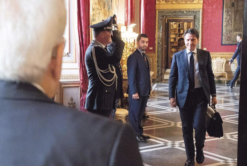 El presidente italiano Sergio Mattarella saluda a un policía mientras camina por el palacio presidencial.