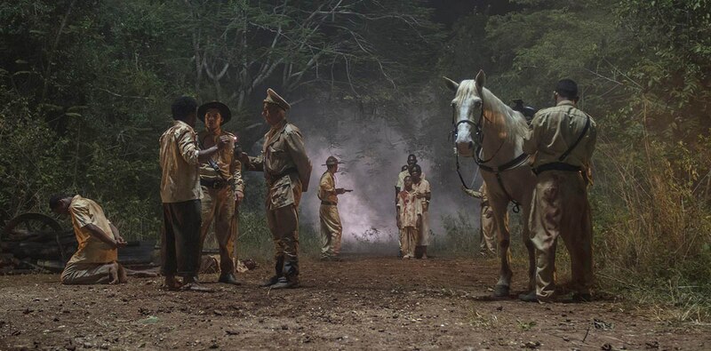 Soldados apuntando con sus armas a un grupo de personas en la selva