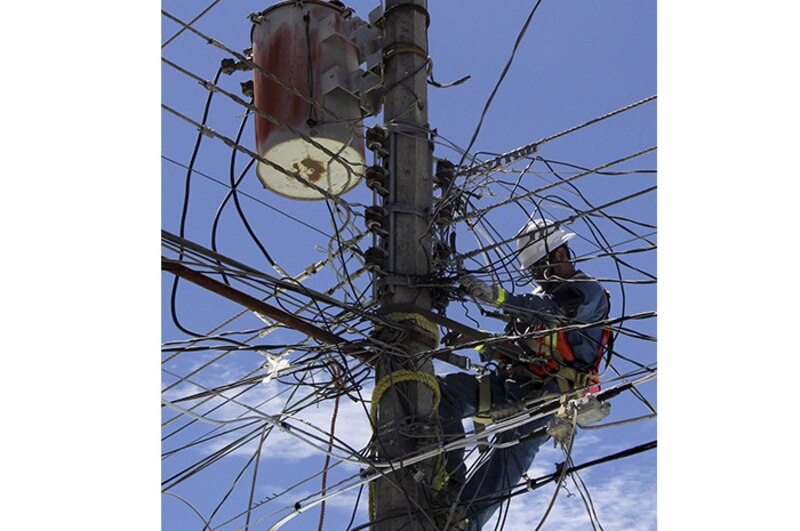 Un trabajador de la compañía eléctrica arregla los cables en un poste.
