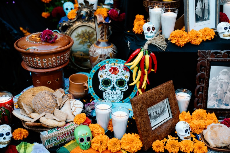 Altar de día de muertos con dulces, velas, calaveras y fotografías