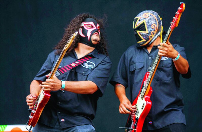 Dos luchadores enmascarados tocan la guitarra en un concierto.