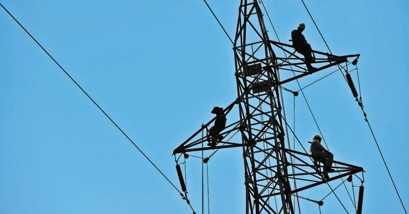 Linieros trabajando en una torre de alta tensión
