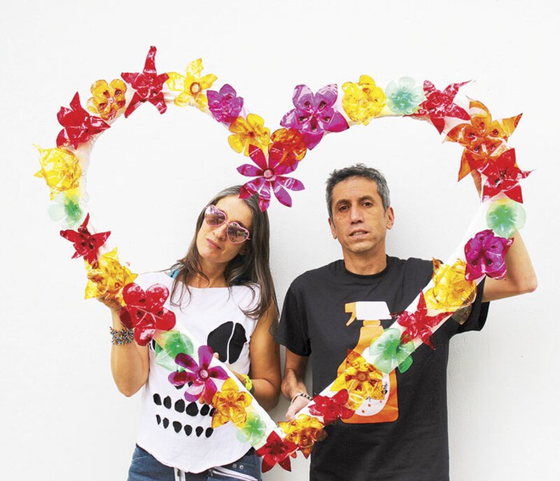 Pareja sosteniendo un corazón hecho de flores de plástico
