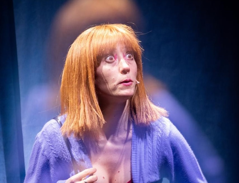 Camila Peralta en escena durante “Suavecita”, cambiando de personaje con una expresión intensa y un juego de luces minimalista.