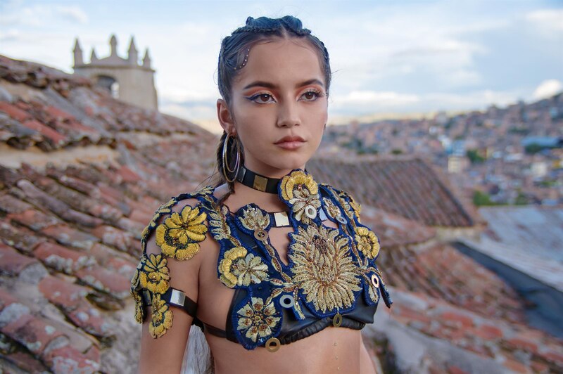 Mujer indígena con traje tradicional en un tejado de Cusco, Perú