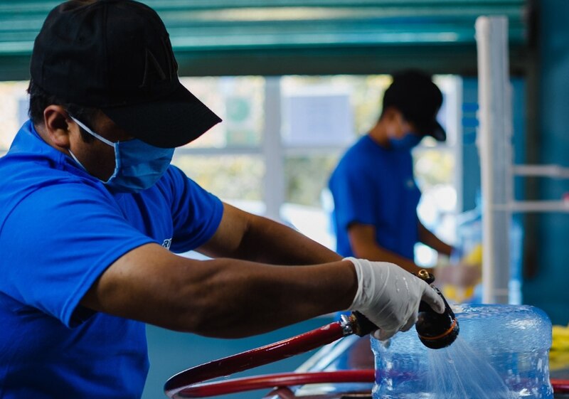 Trabajadores de una fábrica de hielo lavan un bloque de hielo.