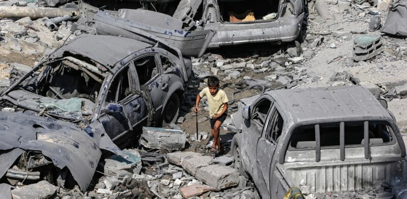 Niño camina entre los escombros de la guerra