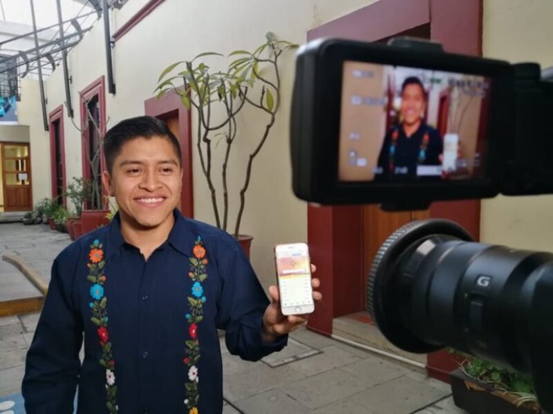 Un joven sostiene un teléfono inteligente en una mano y una cámara de vídeo en la otra.