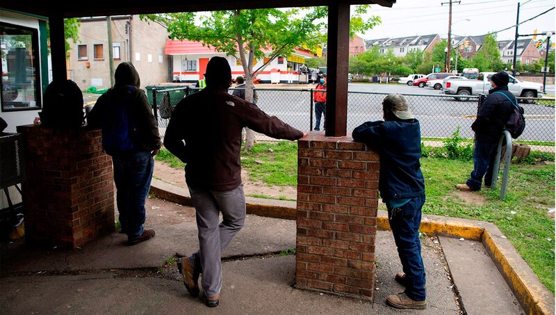 Cuatro hombres esperan en fila para comprar comida en un restaurante de comida rápida.