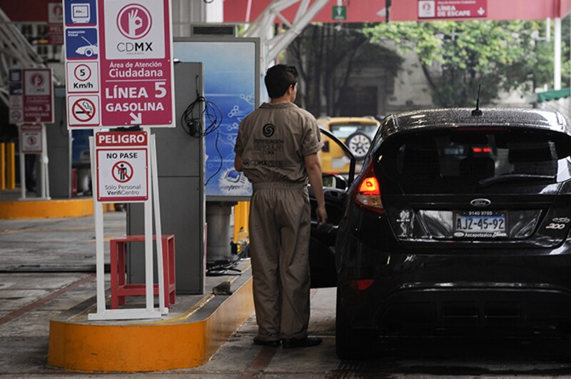 Un empleado de una gasolinera atiende a un cliente.