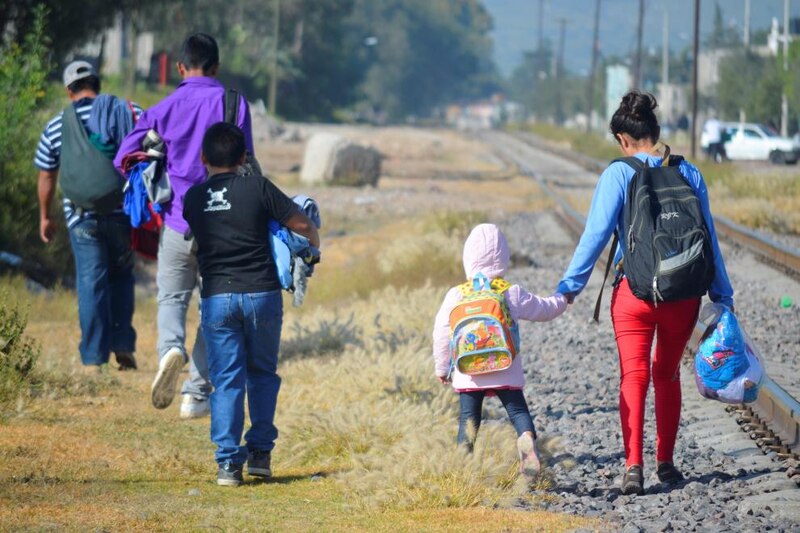 Familia migrante caminando por las vías del tren