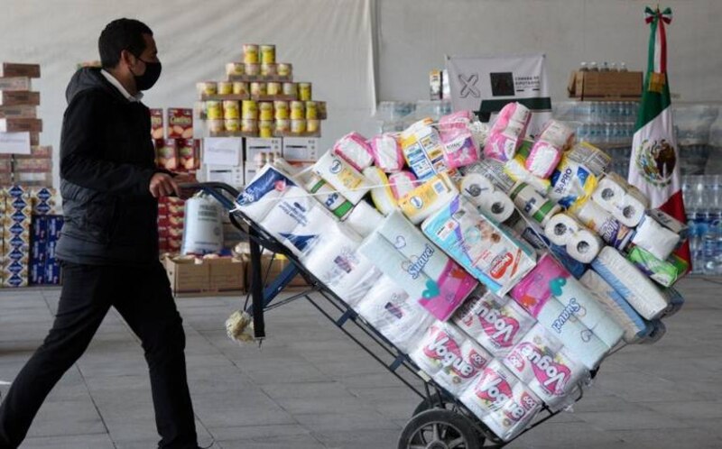 Un hombre empuja un carrito lleno de papel higiénico en un supermercado
