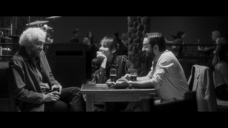 Tres personas están sentadas en una mesa en un bar