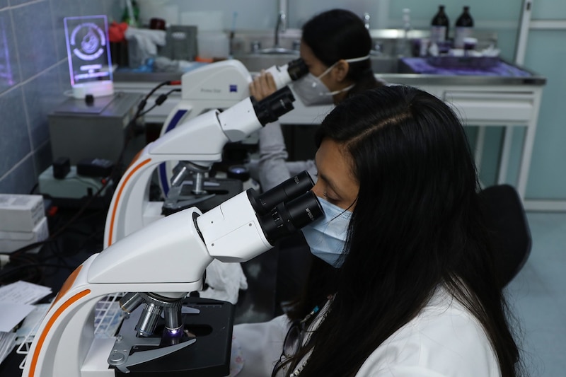 Científicas usando microscopios