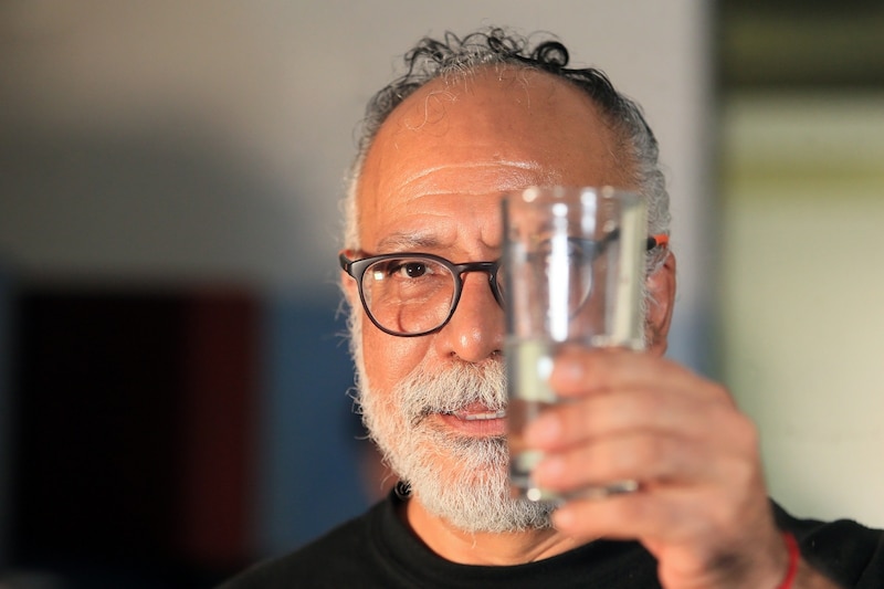 Hombre mirando un vaso de agua