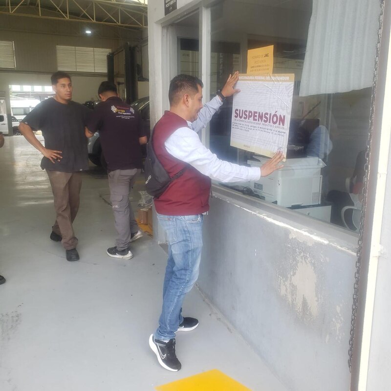Servidor publico de la Procuraduría Federal del Consumidor coloca sellos de suspensión de actividades en la automotriz JAC en Aguascalientes, México